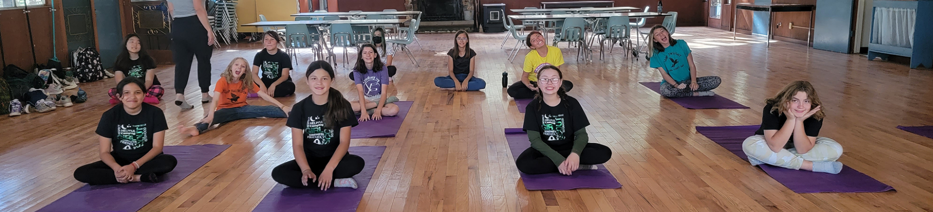  girls smiling sitting on yoga mats 